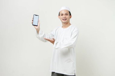 Mutlu Asyalı Müslüman boş telefon ekranı gösteriyor. İnsanlar dini İslam yaşam tarzı kavramını benimsiyor. Ramazan ve Mübarek bayramını kutluyoruz. izole edilmiş arka grupta