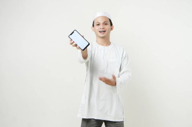 Mutlu Asyalı Müslüman boş telefon ekranı gösteriyor. İnsanlar dini İslam yaşam tarzı kavramını benimsiyor. Ramazan ve Mübarek bayramını kutluyoruz. izole edilmiş arka grupta