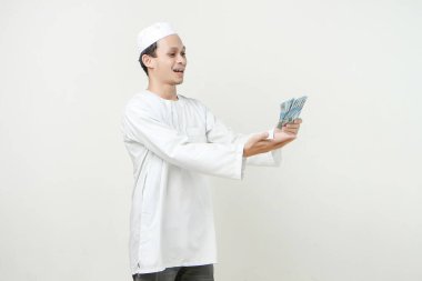 Mutlu Müslüman adam elinde rupiah banknotları tutuyor. İnsanlar dini İslam yaşam tarzı kavramını benimsiyor. Ramazan ve Mübarek bayramını kutluyoruz. izole edilmiş arka grupta