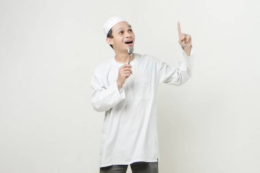 Müslüman adam kaşık tutuyor ve parmağıyla işaret ediyor. İnsanlar dini İslam yaşam tarzı kavramını benimsiyor. Ramazan ve Mübarek bayramını kutluyoruz. izole edilmiş arka grupta