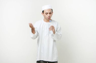 Asyalı Müslüman adam su şişesi tutuyor ve dua ediyor. Avuç içlerini yukarıda tutarak. İnsanlar dini İslam yaşam tarzı kavramını benimsiyor. Ramazan ve Mübarek bayramını kutluyoruz. izole edilmiş arka grupta