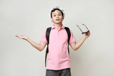 Güneş gözlüğü ve şapka takan Asyalı bir sırt çantalı. Dijital göçebe ve seyahat konsepti. izole edilmiş arkaplanda