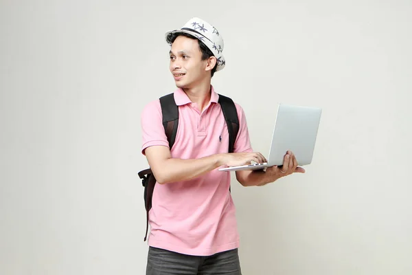 Asian man backpacker holding laptop computer. digital nomad and travelling concept. on isolated background