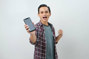 Akıllı telefonu tutan ve izole edilmiş arka planda boş ekran gösteren mutlu Asyalı adam.