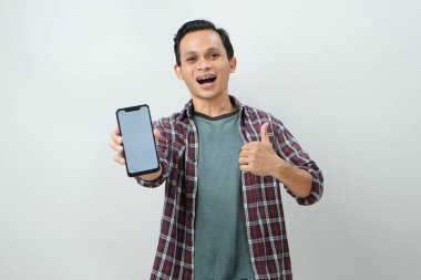 Akıllı telefonu tutan ve izole edilmiş arka planda boş ekran gösteren mutlu Asyalı adam.