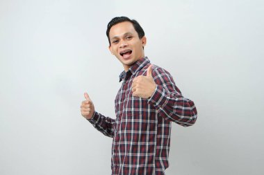 Mutlu Asyalı Endonezyalı adam, izole edilmiş arka planda baş parmak hareketi yapıyor.
