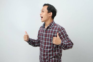 Mutlu Asyalı Endonezyalı adam, izole edilmiş arka planda baş parmak hareketi yapıyor.