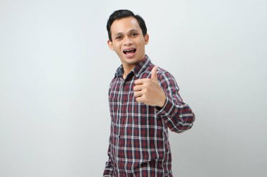 Mutlu Asyalı Endonezyalı adam, izole edilmiş arka planda baş parmak hareketi yapıyor.