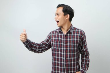 Mutlu Asyalı Endonezyalı adam, izole edilmiş arka planda baş parmak hareketi yapıyor.