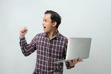 Asyalı mutlu adam dizüstü bilgisayarını izole edilmiş arka planda tutuyor.