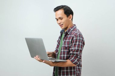 Asyalı mutlu adam dizüstü bilgisayarını izole edilmiş arka planda tutuyor.