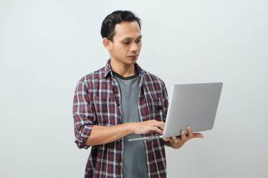 Asyalı mutlu adam dizüstü bilgisayarını izole edilmiş arka planda tutuyor.