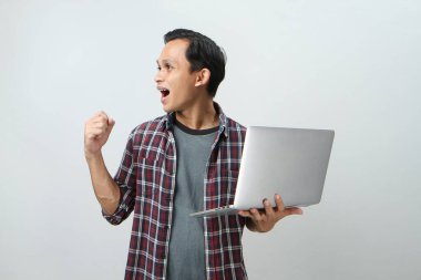 Asyalı mutlu adam dizüstü bilgisayarını izole edilmiş arka planda tutuyor.