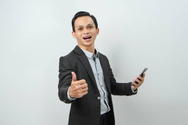 Asyalı Endonezyalı takım elbiseli iş adamının portresi. Sllie 'li akıllı telefonu tutuyor ve parmak hareketlerini izole edilmiş arka planda gösteriyor.