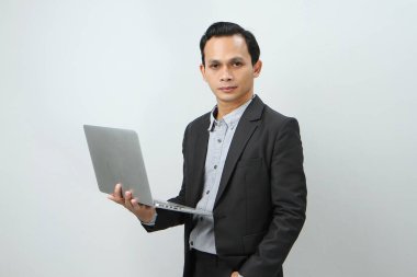 Mutlu Asyalı takım elbiseli iş adamı izole edilmiş arka planda akıllı telefon ve dizüstü bilgisayar tutuyor.