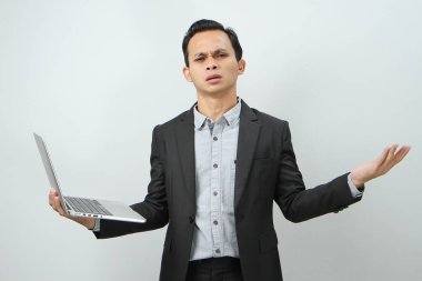 Kızgın, Asyalı, takım elbiseli iş adamı dizüstü bilgisayarını izole edilmiş arka planda tutuyor.