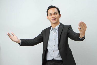 Mutlu, kendine güvenen Endonezyalı, takım elbiseli iş adamı izole edilmiş arka planda el hareketi yapıyor.