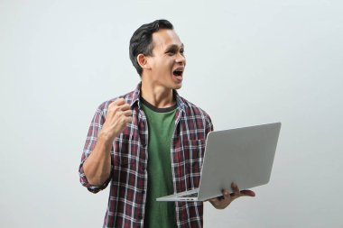 Asyalı mutlu adam dizüstü bilgisayarını izole edilmiş arka planda tutuyor.