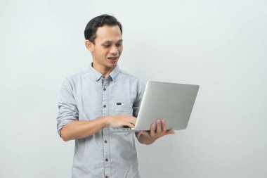 Asyalı mutlu adam dizüstü bilgisayarını izole edilmiş arka planda tutuyor.