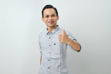 Neşeli, mutlu, kendinden emin Endonezyalı, parmak kaldıran, izole edilmiş bir geçmişi olan bir adam.