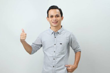 Neşeli, mutlu, kendinden emin Endonezyalı, parmak kaldıran, izole edilmiş bir geçmişi olan bir adam.