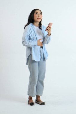 Asyalı Endonezyalı bir kadının arka planda aç bir jestle akıllı telefon tutmasının uzun bir çekimi.