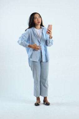 Asyalı Endonezyalı bir kadının arka planda aç bir jestle akıllı telefon tutmasının uzun bir çekimi.