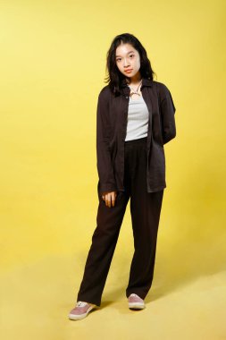 Endonezyalı kadının izole edilmiş sarı arka planda günlük kıyafet giydiği uzun bir çekim.