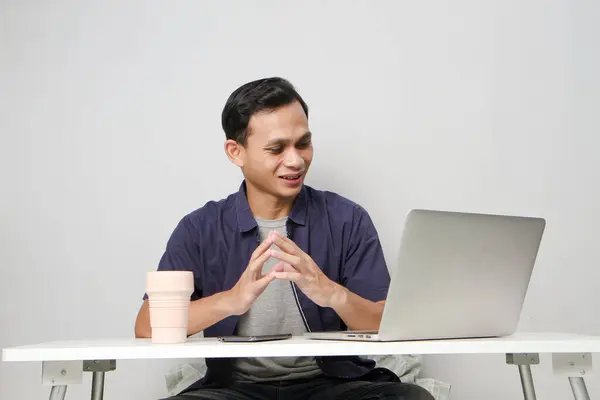 stock image joyfull happy asian man at workplace while sitting in front of laptop computer. on isolated background