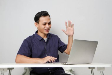 İş yerinde bilgisayarın önünde otururken videodaki mutlu Asyalı adam online toplantı yapıyor. izole edilmiş arkaplanda