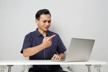 Videodaki neşeli Asyalı adam internetteki toplantıda dizüstü bilgisayarın önünde otururken suçlamada bulundu. izole edilmiş arkaplanda