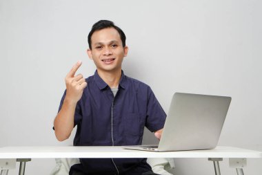 Videodaki neşeli Asyalı adam internetteki toplantıda dizüstü bilgisayarın önünde otururken suçlamada bulundu. izole edilmiş arkaplanda