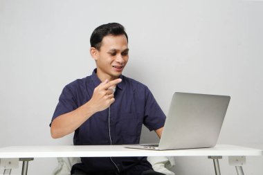 Videodaki neşeli Asyalı adam internetteki toplantıda dizüstü bilgisayarın önünde otururken suçlamada bulundu. izole edilmiş arkaplanda