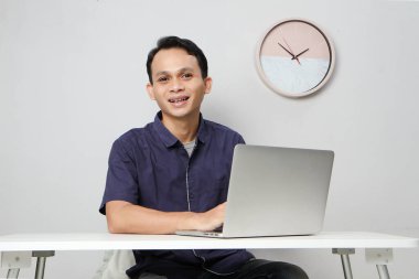 İş yerinde dizüstü bilgisayarın önünde oturan neşeli, mutlu Asyalı adam. izole edilmiş arkaplanda