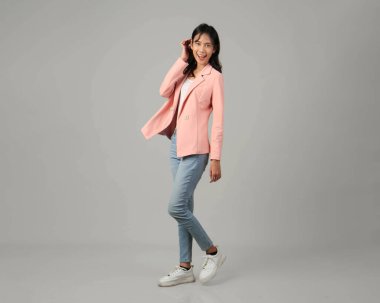 Tam uzunlukta mutlu Asyalı kadınlar resmi kıyafet giyerek izole edilmiş arka planda yürüyüş jestleri yaparak çekim yaparlar.