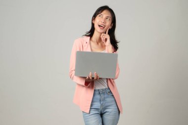 Asyalı mutlu bir kadın resmi kıyafet giyiyor dizüstü bilgisayarını izole edilmiş arka planda tutuyor.