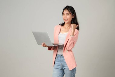 Mutlu Asyalı kadın resmi kıyafet giyiyor dizüstü bilgisayarı tutuyor ve izole edilmiş arka plandan vazgeçiyor.