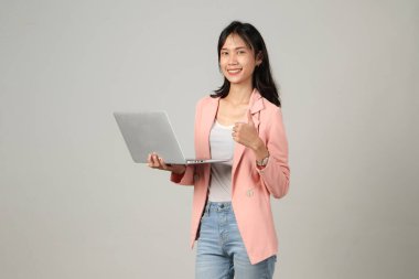 Mutlu Asyalı kadın resmi kıyafet giyiyor dizüstü bilgisayarı tutuyor ve izole edilmiş arka plandan vazgeçiyor.