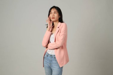 Soyutlanmış arka planda resmi kıyafet giyen düşünceli Asyalı kadın.