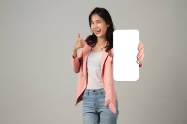 Mutlu Asyalı kadın izole edilmiş arka planda cep telefonu ekranı gösteriyor.