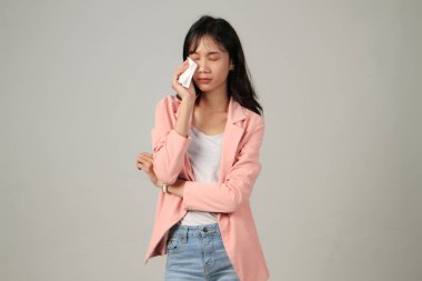 Üzgün Asyalı kadın, izole edilmiş arka planda gözyaşlarını kağıt mendille siliyor.