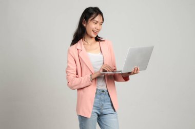 Asyalı mutlu bir kadın resmi kıyafet giyiyor dizüstü bilgisayarını izole edilmiş arka planda tutuyor.