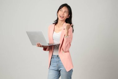 Mutlu Asyalı kadın resmi kıyafet giyiyor dizüstü bilgisayarı tutuyor ve izole edilmiş arka plandan vazgeçiyor.