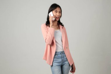 Mutlu Asyalı kadın telefonda konuşuyor. Yüzünde heyecanlı bir ifade var.