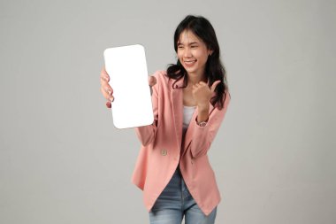 Mutlu Asyalı kadın izole edilmiş arka planda cep telefonu ekranı gösteriyor.