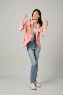 Mutlu Asyalı kadının yumruğunu kaldırdığı uzun bir çekim. Ayrı bir arkaplanda resmi kıyafet giymek