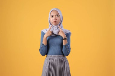 İzole edilmiş sarı arka planda düşünceli Asyalı Müslüman kadın.