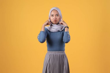 İzole edilmiş sarı arka planda düşünceli Asyalı Müslüman kadın.