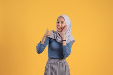 Asyalı Endonezyalı Müslüman kadın izole edilmiş sarı bakkalda parmak hareketi yapıyor ve bağırıyor.