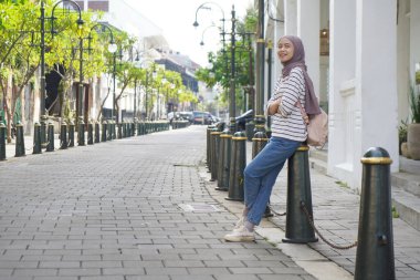 Asyalı Müslüman kadın Kota Lama ya da Old Town CIty, Semarang, Yogyakarta 'da sokak kenarındaki direğe yaslanıp duruyor.